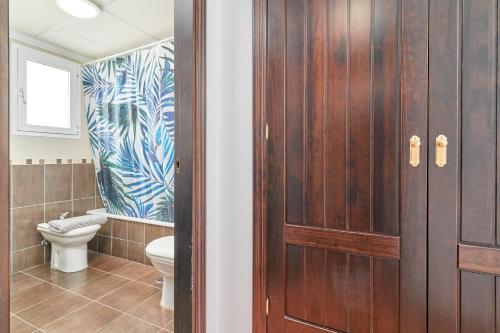 a bathroom with a toilet and a wooden door at Casa Axarquia 2 in Vélez-Málaga