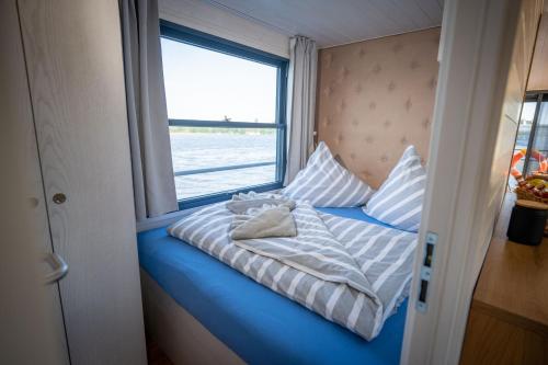 a bed sitting in a room with a window at Naturerlebnis Hausboot Frigga Woma in Fürstenberg