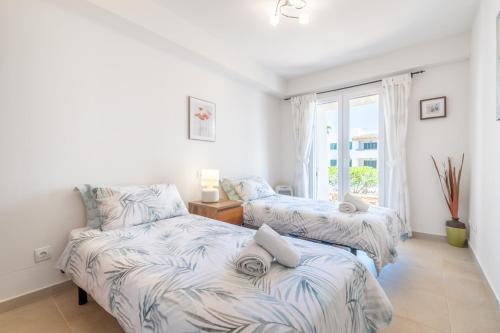 two beds in a room with a window at Cala Egos Villa - S'Estel in Cala d´Or