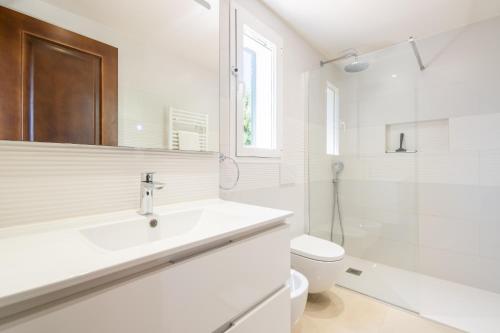 a white bathroom with a sink and a toilet at Cala Egos Villa - S'Estel in Cala d´Or