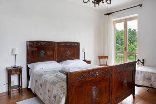 a large wooden bed in a bedroom with a window at Casa Pianezzo Dogliani in Dogliani