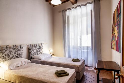 two beds in a room with a window at Residenza Palazzo Ghio in Scansano