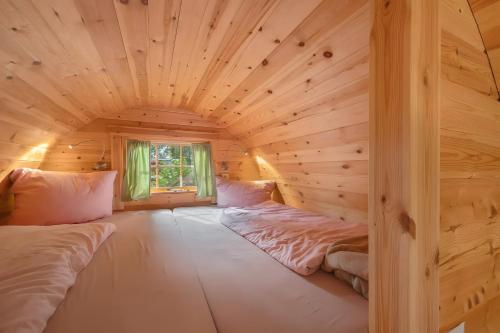 a room with two beds in a log cabin at das Fass de Olle Uhlhoff in Barlt