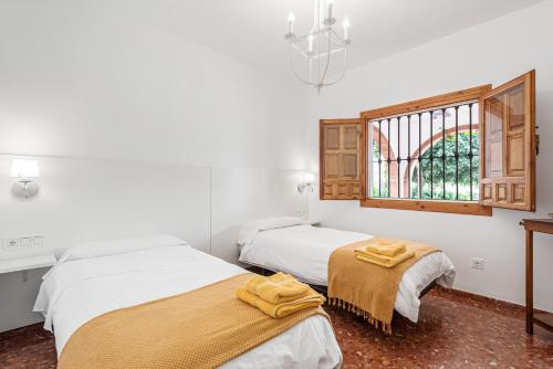 two beds in a room with a window at Finca Llano de Fe in Málaga