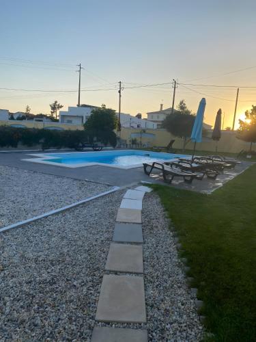 a pool with picnic tables and umbrellas in a yard at Casa Amarela in Ponte de Vagos