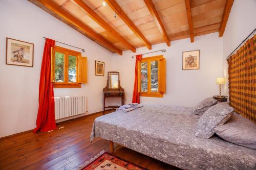 a bedroom with a bed and a table and windows at Tramuntana in Valldemossa