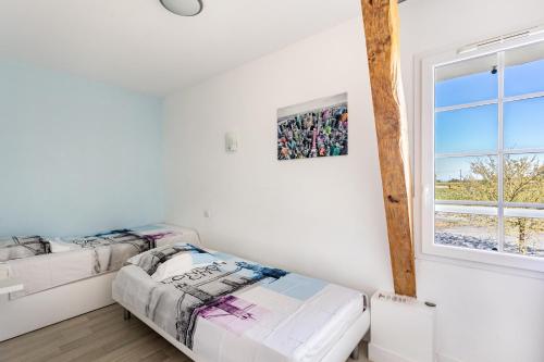 two beds in a room with a window at Gîte De L'orchidée in Saint-Épain