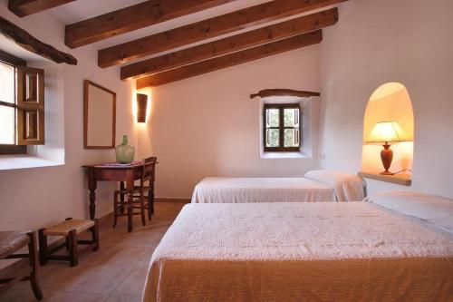 a room with three beds and a table and a window at Butxaco in Pollença
