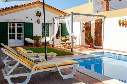 a group of chairs sitting next to a swimming pool at Casa de Jardim in Ponte de Sor