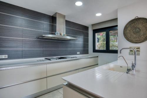 a white kitchen with a stove and a sink at Design villa with sea views in San Pol de Mar