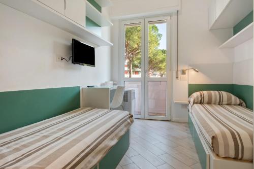 two beds in a room with a tv and a window at Solaria in Rapallo