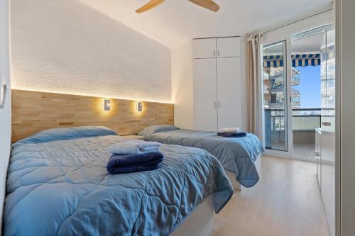 a bedroom with two beds and a large window at Tirreno 304 in La Pineda
