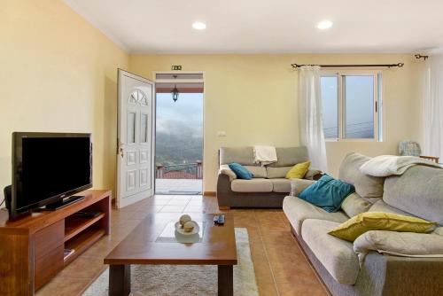 a living room with a couch and a tv at Vinháticos House in São Vicente