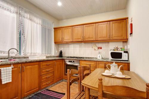 a kitchen with wooden cabinets and a wooden table at Vinháticos House in São Vicente