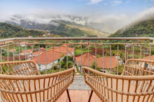 two chairs sitting on a balcony looking at the mountains at Vinháticos House in São Vicente