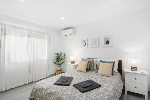 a white bedroom with a bed with two towels on it at Apartamento Acácia in Vale do Lobo