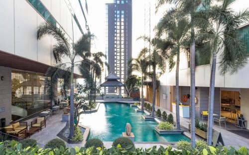 an indoor pool in a building with palm trees at Jasmine City Hotel in Bangkok