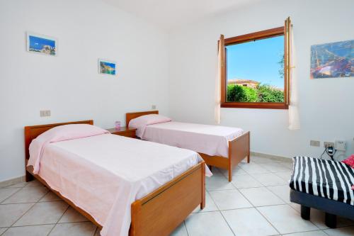 two beds in a room with a window at Villa Bianca in San Teodoro