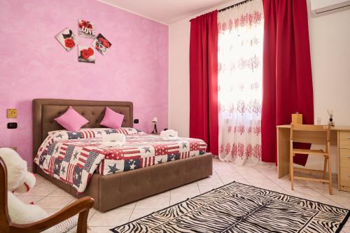a bedroom with pink walls and a bed and a desk at Casa laureta in Piombino