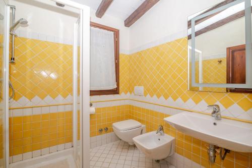 a yellow tiled bathroom with a toilet and a sink at Residenza Conti Porto Istana in Porto Istana