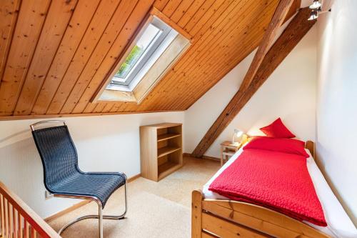 a bedroom with a bed and a chair in a attic at Ferienhaus Mülhaupt in Ühlingen-Birkendorf