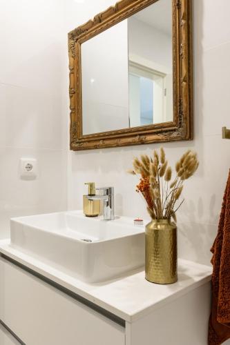 a bathroom with a white sink and a mirror at Aurora do Furadouro l in Ovar