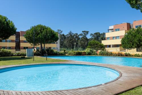 a large swimming pool in a park with buildings in the background at Aurora do Furadouro l in Ovar