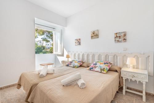 two beds in a white room with a window at Bungalow Cala Dor 27 in Cala d´Or