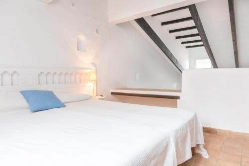 a white bedroom with a blue pillow on a bed at Cala Serena Beach 6 in Felanitx