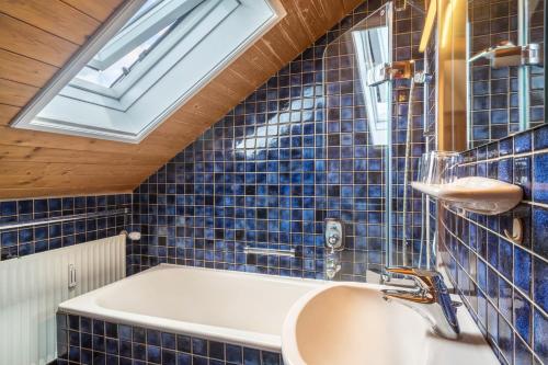 a bathroom with blue tiles and a sink and a window at Haus Kremeier in Kressbronn am Bodensee