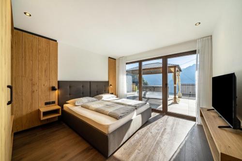 a bedroom with a bed and a large window at Sunnseitn Lodge Exclusive Panorama in Moso