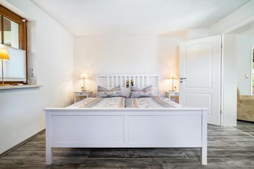 a white bed in a white bedroom with two lamps at Ferienwohnung Eichenhof in Blankensee