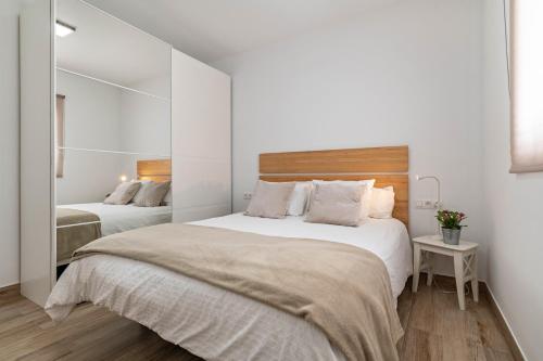 a white bedroom with two beds and a mirror at Casa Majina in El Islote