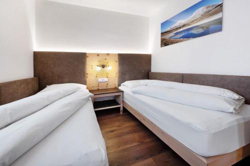 two beds in a room with white sheets at Apartments Antersi Claudia in San Vigilio Di Marebbe