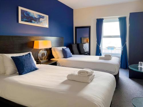 a hotel room with two beds with blue walls at The Esplanade Hotel by Compass Hospitality in Paignton