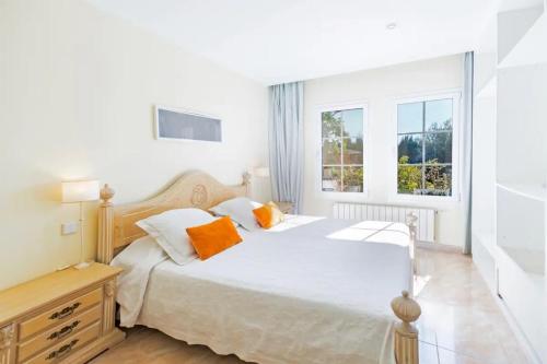 a bedroom with a large white bed with orange pillows at Alcanada Paradise in Alcudia