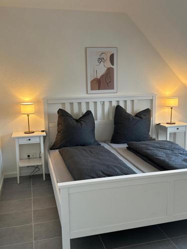 a white bed with two pillows and two lamps at Ferienwohnung Seescheune in Bodman-Ludwigshafen