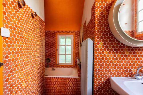 an orange bathroom with a tub and a sink at La Closerie du Cassereau in Vernou-sur-Brenne