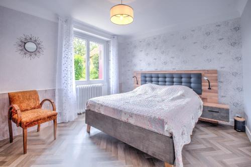 a bedroom with a bed and a chair and a window at Maison familiale à Archignac in Archignac