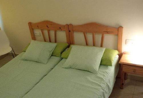 a bed with two green pillows and a wooden headboard at Los Cristianos plaza property in Los Cristianos