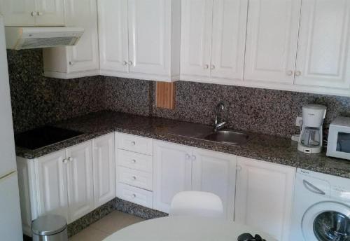a kitchen with white cabinets and a sink at Los Cristianos plaza property in Los Cristianos