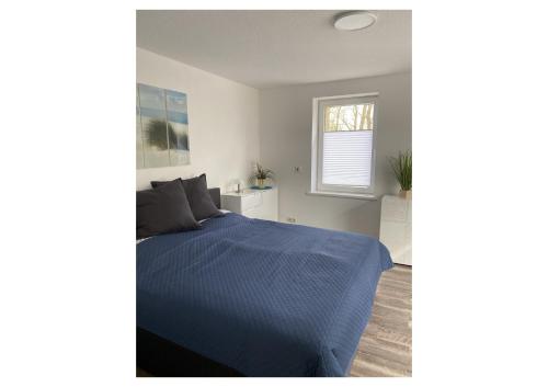 a bedroom with a blue bed and a window at Ferienwohnung Auf dem Hohm in Holssel