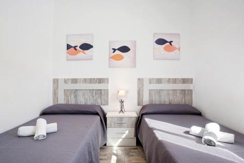 two beds in a bedroom with paintings on the wall at Casa Maria Jose in Cádiz