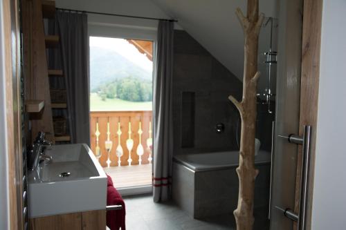 ein Bad mit einem Waschbecken, einer Badewanne und einem Fenster in der Unterkunft Bramsauerhof in Faistenau