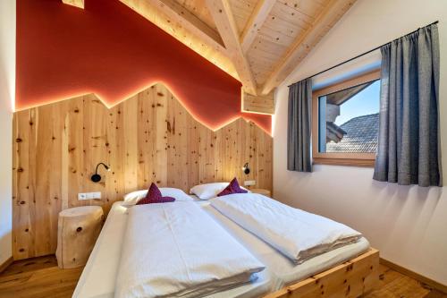 a bedroom with a bed with a wooden wall at Ferienwohnung Gruberhof in Verano