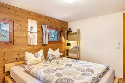 a bed in a room with a wooden wall at Ferienhaus am Berg in Hirschau