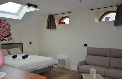 a bedroom with a bed and a couch and two windows at Chambres D'hôtes Le Fer À Cheval in Montreuil-sur-Maine