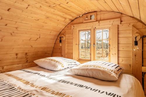 a bed in a wooden cabin with two pillows at Les Chouchous du Garthieu in Hourtin