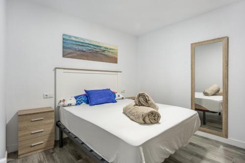 a white bedroom with a bed with a mirror at Apartamento Tom-Isi in Rota