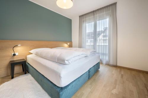 a bedroom with a large bed and a large window at Avia Living in Brunico